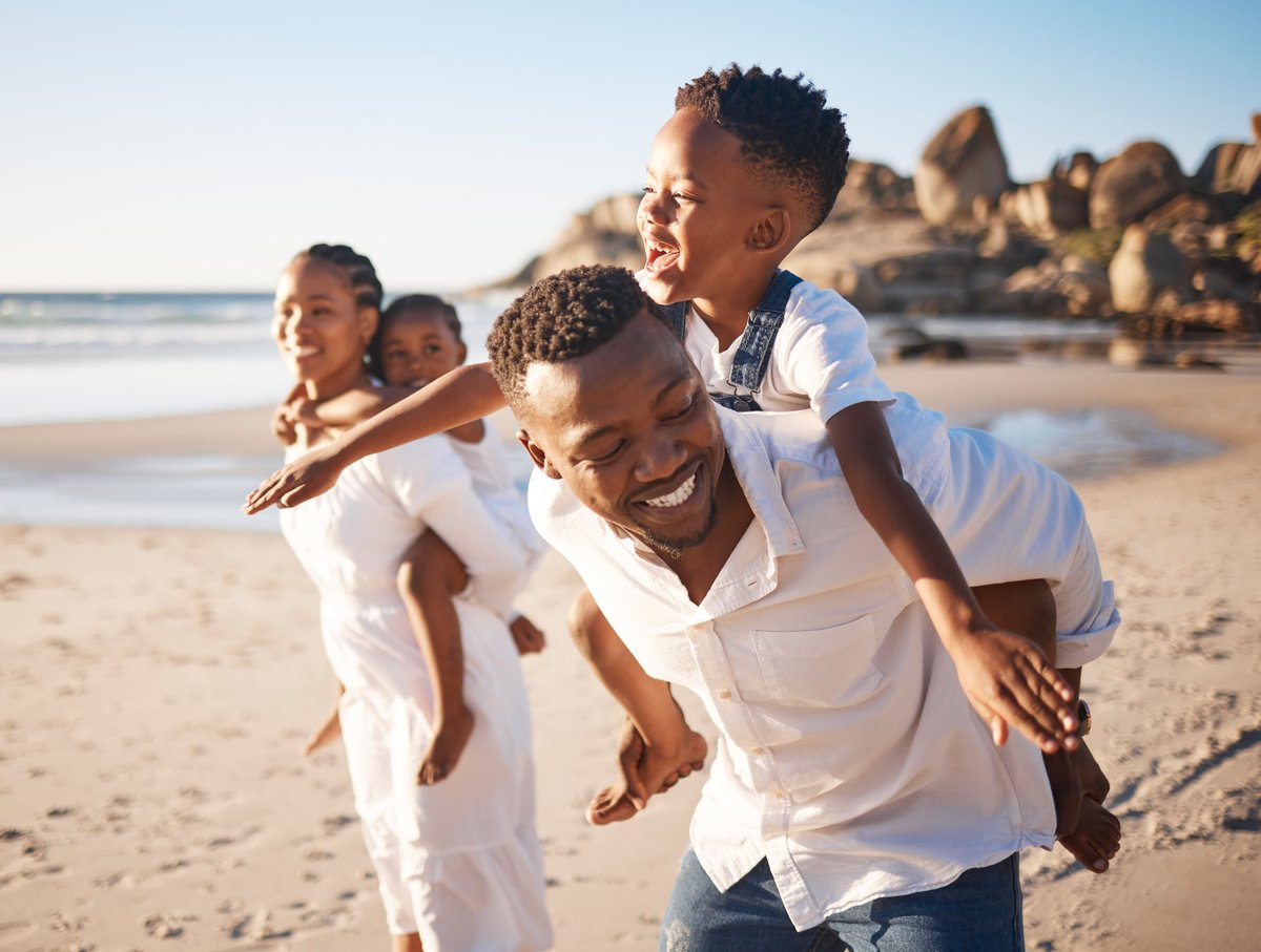 A joyful Black family playing together on a Jamaican beach
